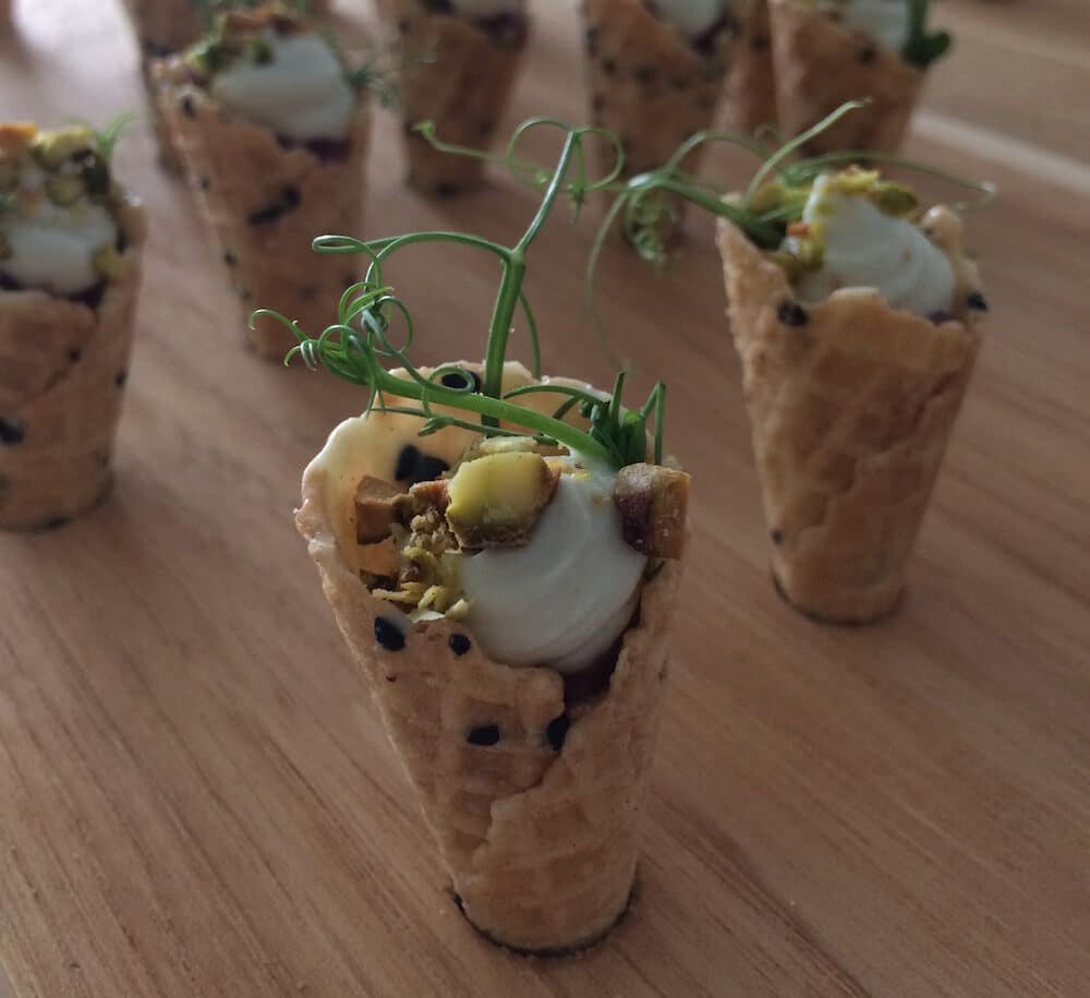Sesame cone with wine poached pear, blue cheese mousse, toasted pistachio, and UC-grown peashoots